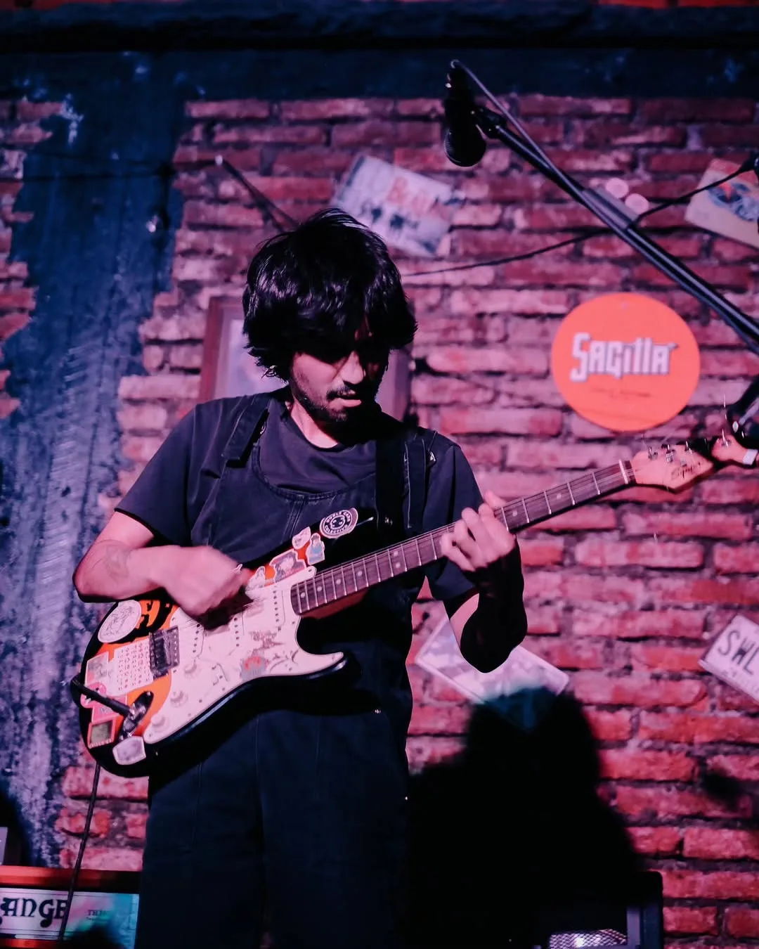Guitarrista de Phuyu y la Fantasma frente a un muro de ladrillo