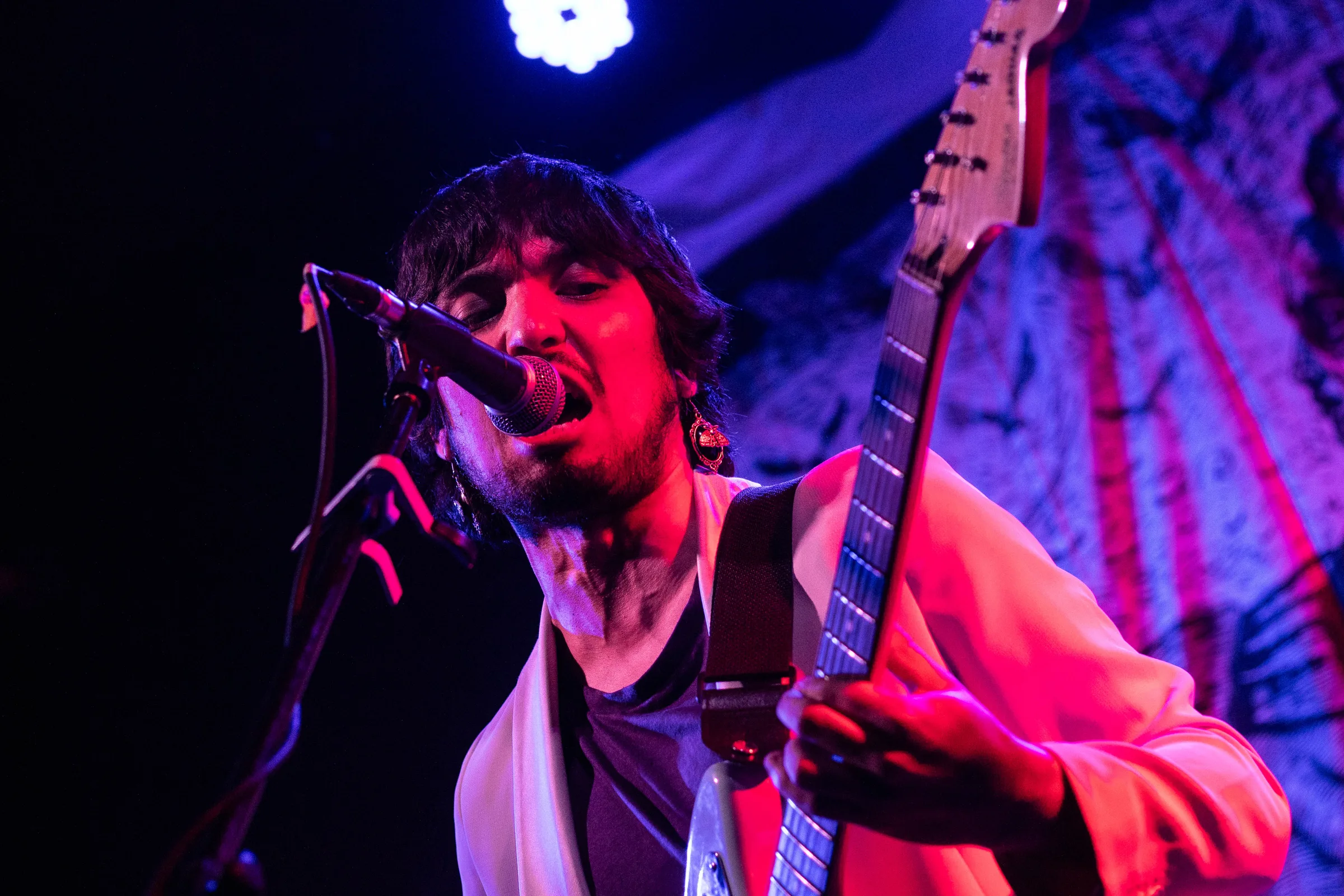 Rodrigo Romero canta al micrófono y toca guitarra eléctrica en un concierto de Phuyu y la Fantasma